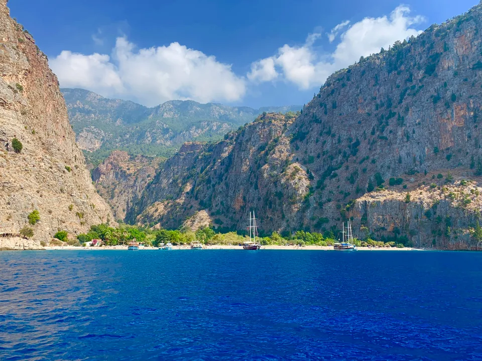 Bateaux devant la plage et les falaises de la vallée des Papillons près d’Ölüdeniz